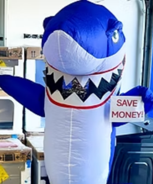 Dealio, an Appliance Shark mascot holding a Save Money sign